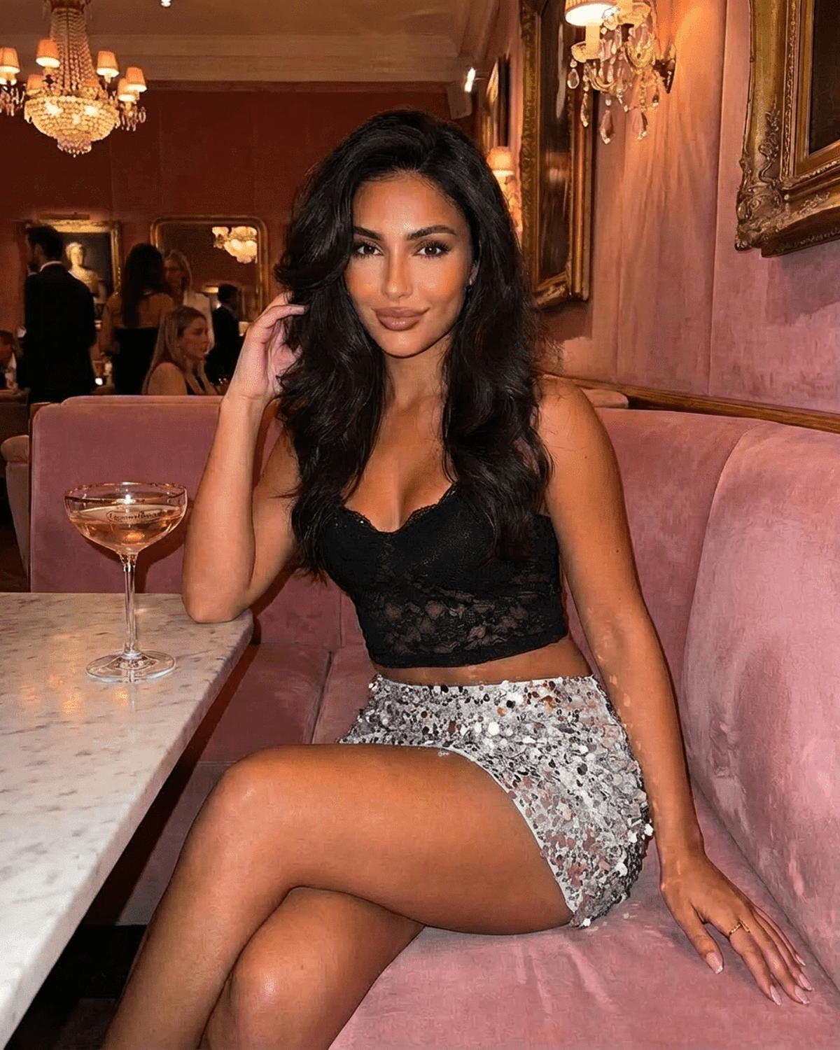 Woman wearing a Sterling Mini Skirt with silver sequin hem, sitting in a stylish setting, ideal for glamorous outings.