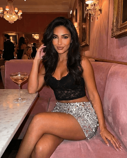 Woman wearing a Sterling Mini Skirt with silver sequin hem, sitting in a stylish setting, ideal for glamorous outings.