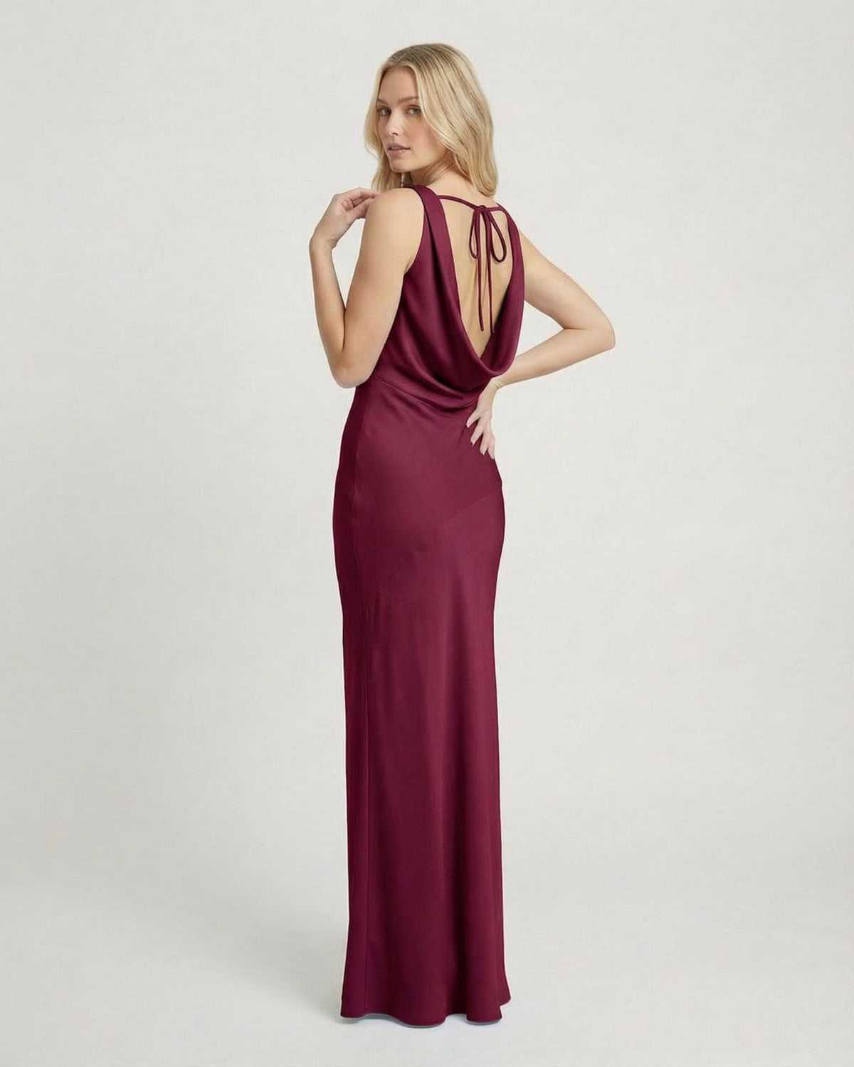 Back view of a woman wearing the Verona Maxi Dress by SLIMONA in a rich burgundy shade, featuring a cowl neckline.