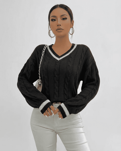 Model wearing SLIMONA Verona Sweater, a cable knit V-neck pullover, styled with white jeans.