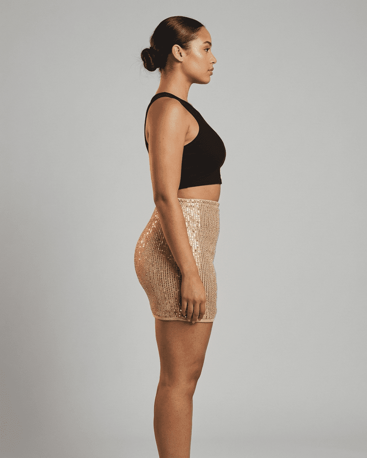 Model showcasing Lumiere Mini Skirt by SLIMONA, high waist, sequin bodycon design, side view.