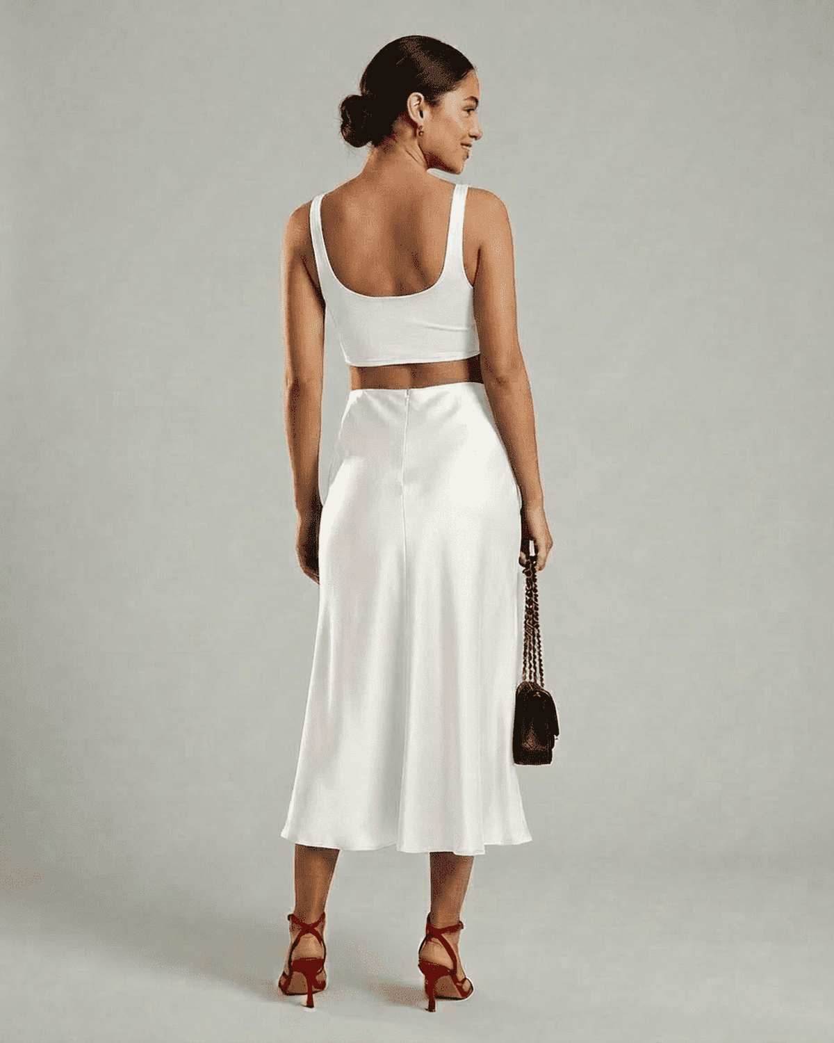 Woman wearing Luna Midi Skirt by SLIMONA, showcasing its elegant satin mermaid design and flowing silhouette.