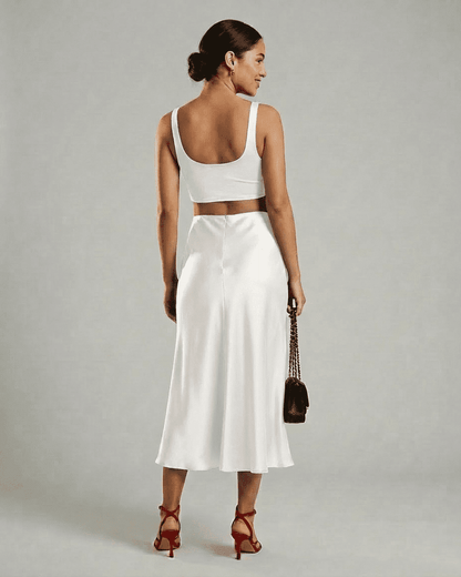 Woman wearing Luna Midi Skirt by SLIMONA, showcasing its elegant satin mermaid design and flowing silhouette.