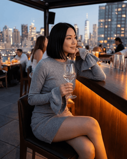 Woman in elegant ruffled sleeve dress holding a glass, showcasing the Luna Mini Dress by SLIMONA.