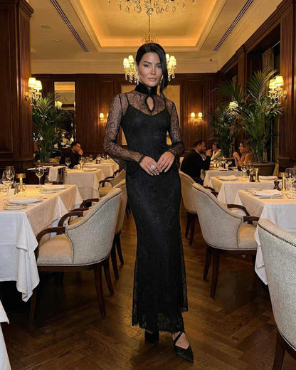 Woman wearing Noctavia Maxi Dress by Lauven, black lace long sleeve bodycon dress with stand collar in elegant restaurant.