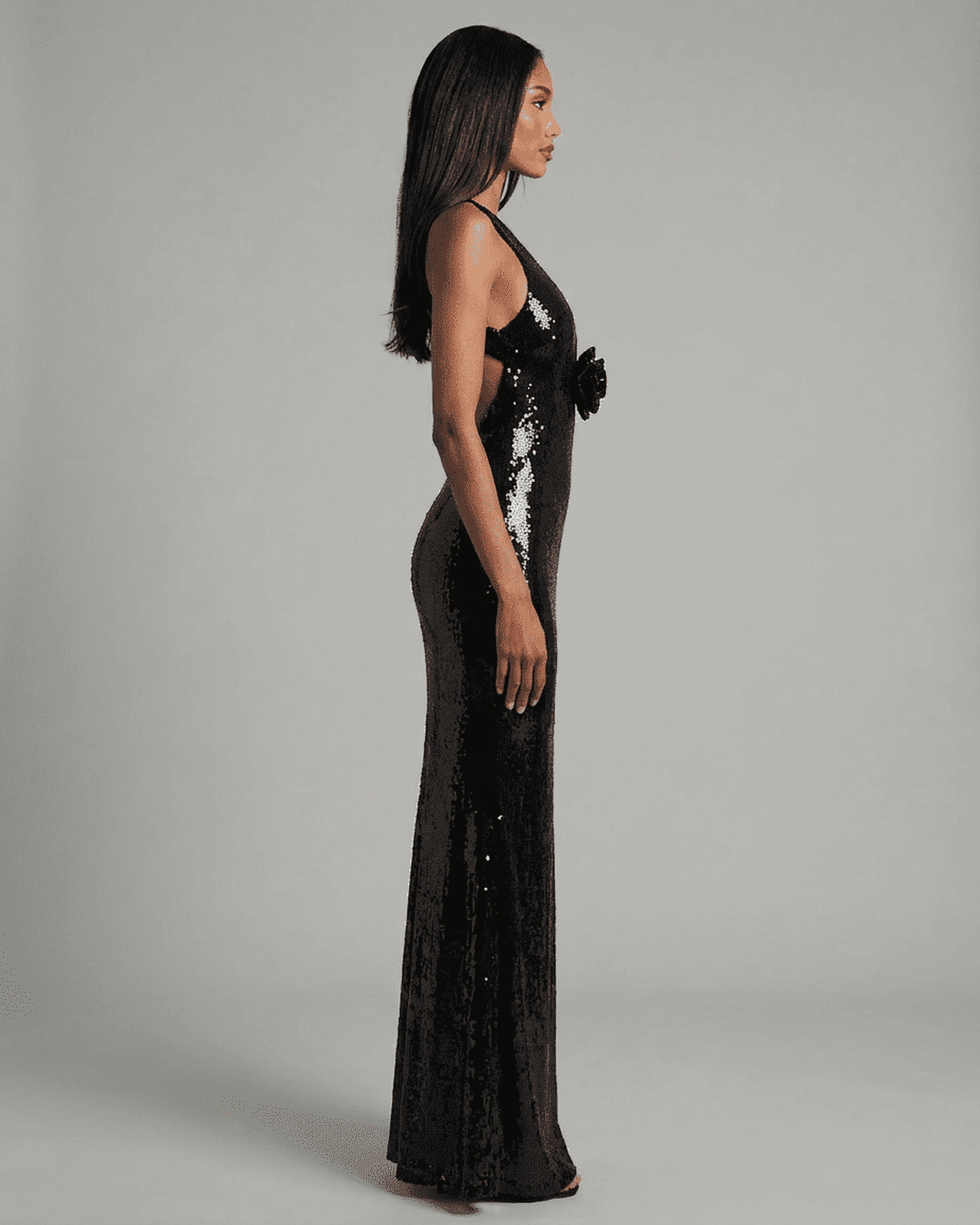 Noiré Maxi Dress by SLIMONA, backless black sequin dress with floral detail, side view showcasing elegant silhouette.