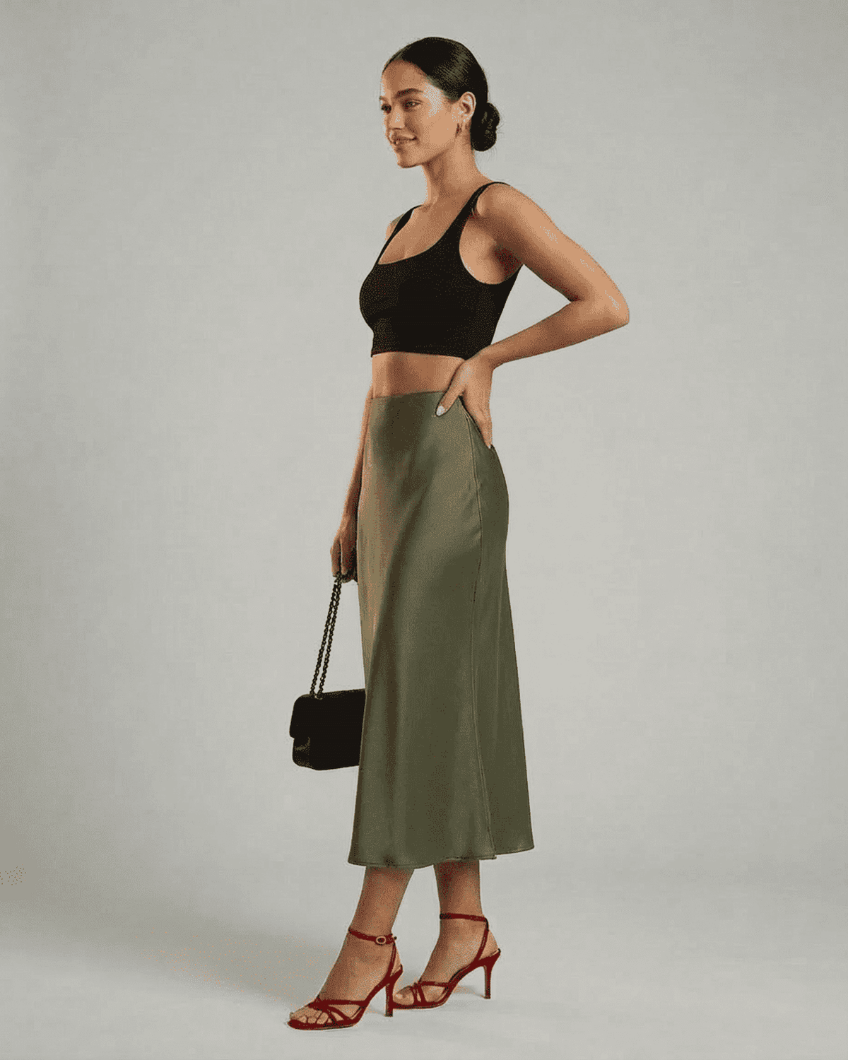Olivia Midi Skirt in olive green by SLIMONA, featuring a satin mermaid design, styled with a black crop top and red heels.