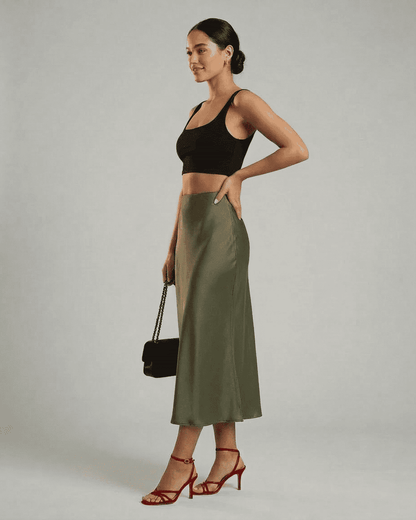 Olivia Midi Skirt in olive green by SLIMONA, featuring a satin mermaid design, styled with a black crop top and red heels.