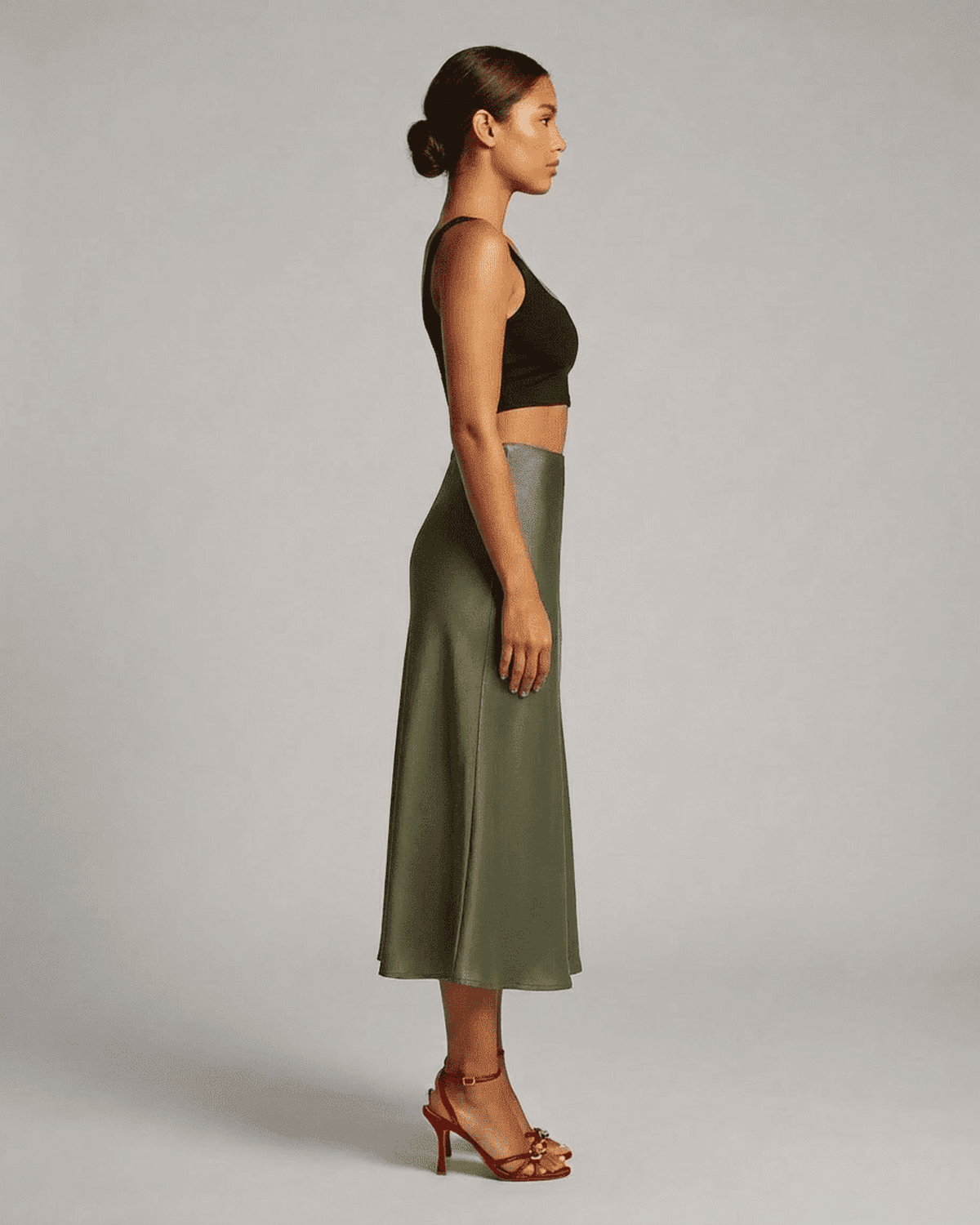 Model showcasing the Olivia Midi Skirt by SLIMONA in olive green, highlighting elegant satin flow and flattering silhouette.