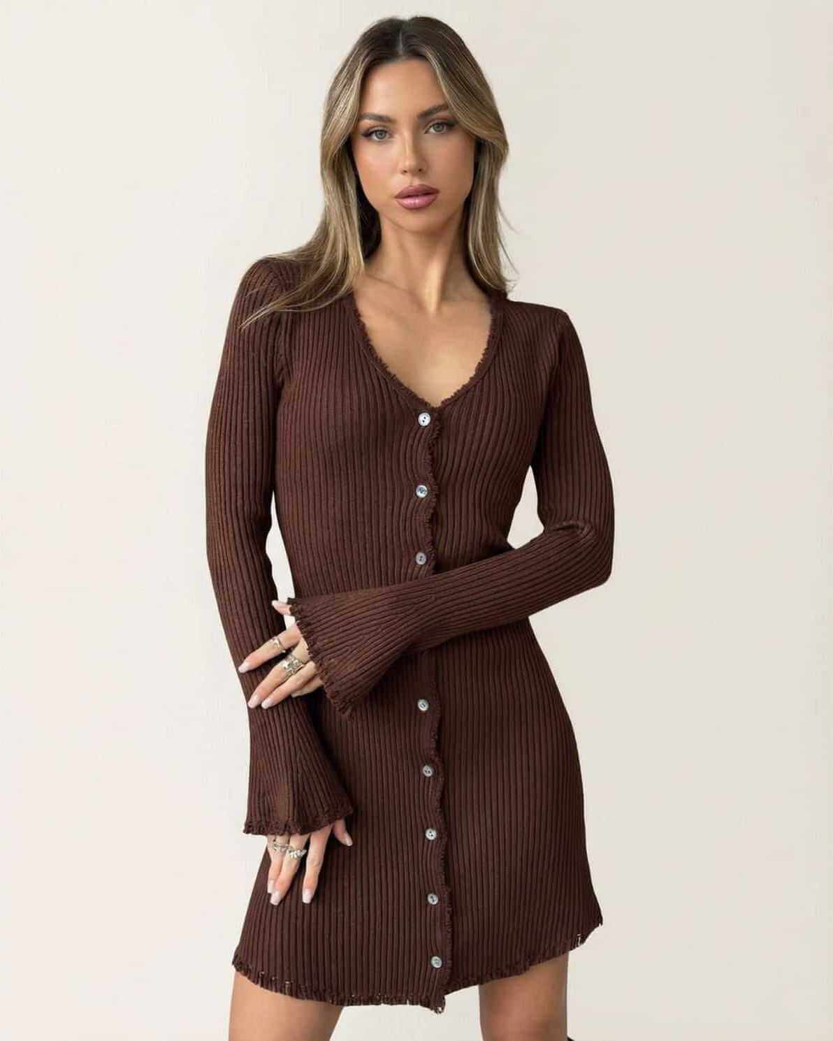 Model wearing the Orion Mini Dress by Lauven, a ribbed bodycon mini dress with flare sleeves and button details in deep chocolate brown.