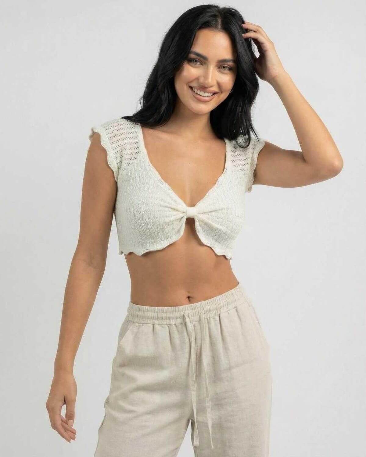 Smiling model wearing Calista Top by Lauven, a women's cotton knit top with lettuce trim and V-neck design.