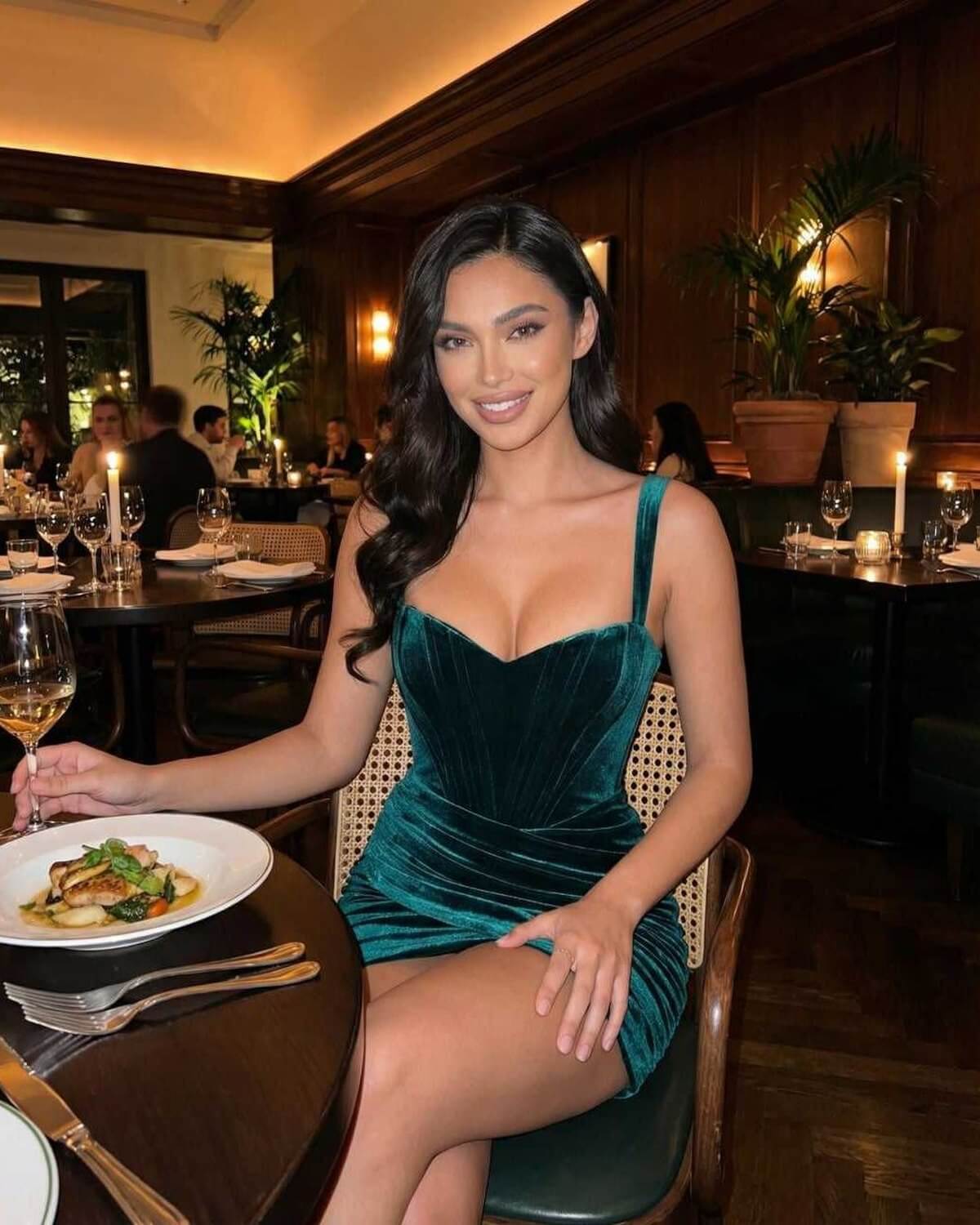 Orion Mini Dress by Lauven in luxe velvet, showcasing a rich teal hue and a chic asymmetrical silhouette at a restaurant.