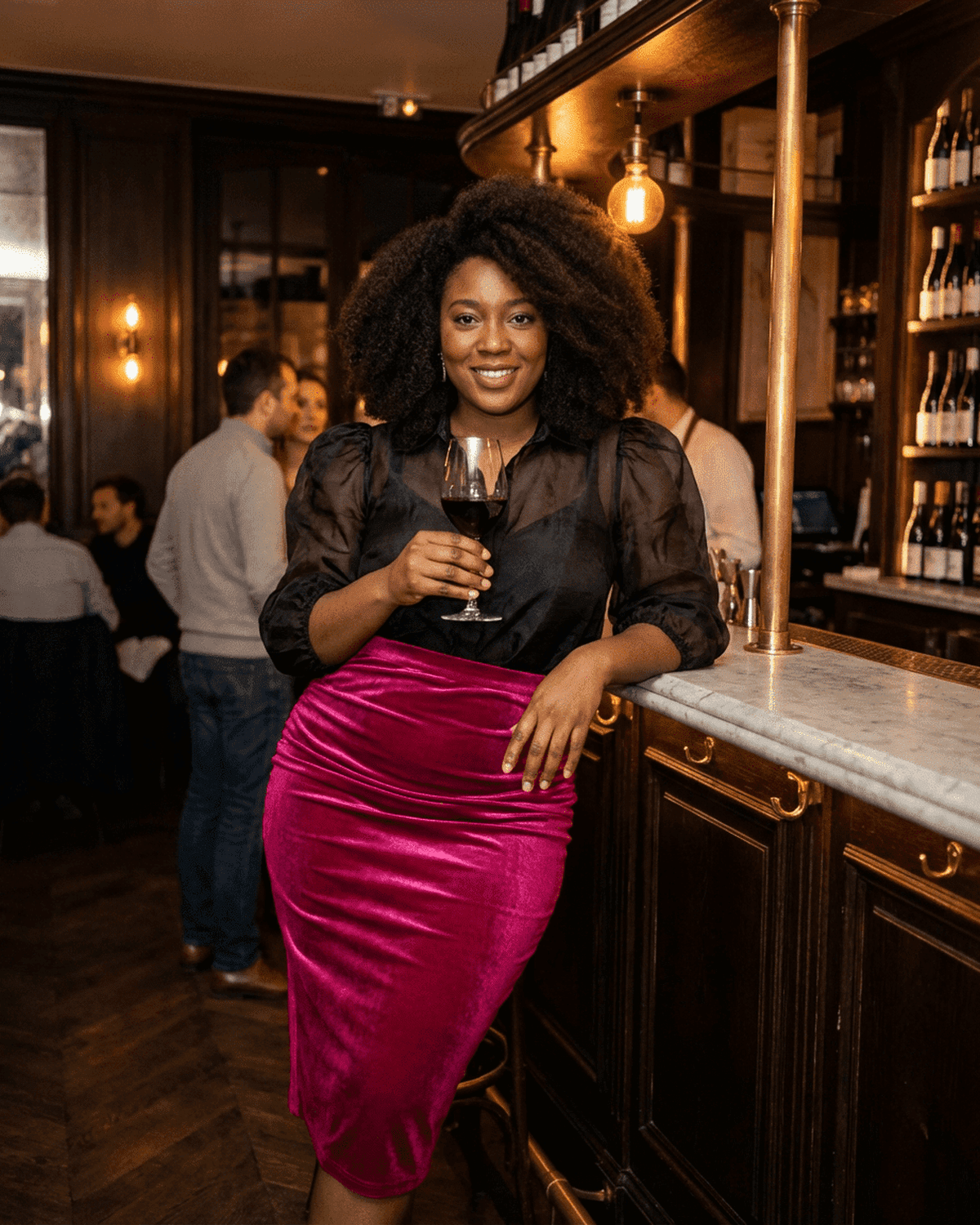 Woman in a velvet pink Rosalia Midi Skirt by SLIMONA, elegantly posing with a glass in a stylish bar.
