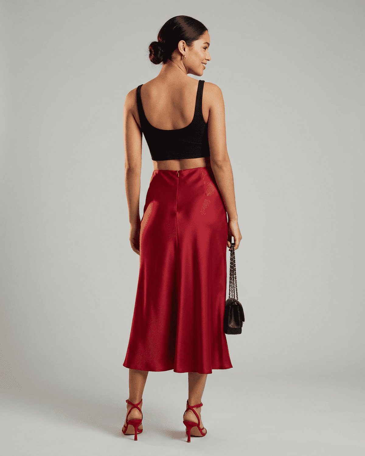 Model showcasing the elegant Rosalia Midi Skirt by SLIMONA in rich red, paired with a crop top and stylish heels.