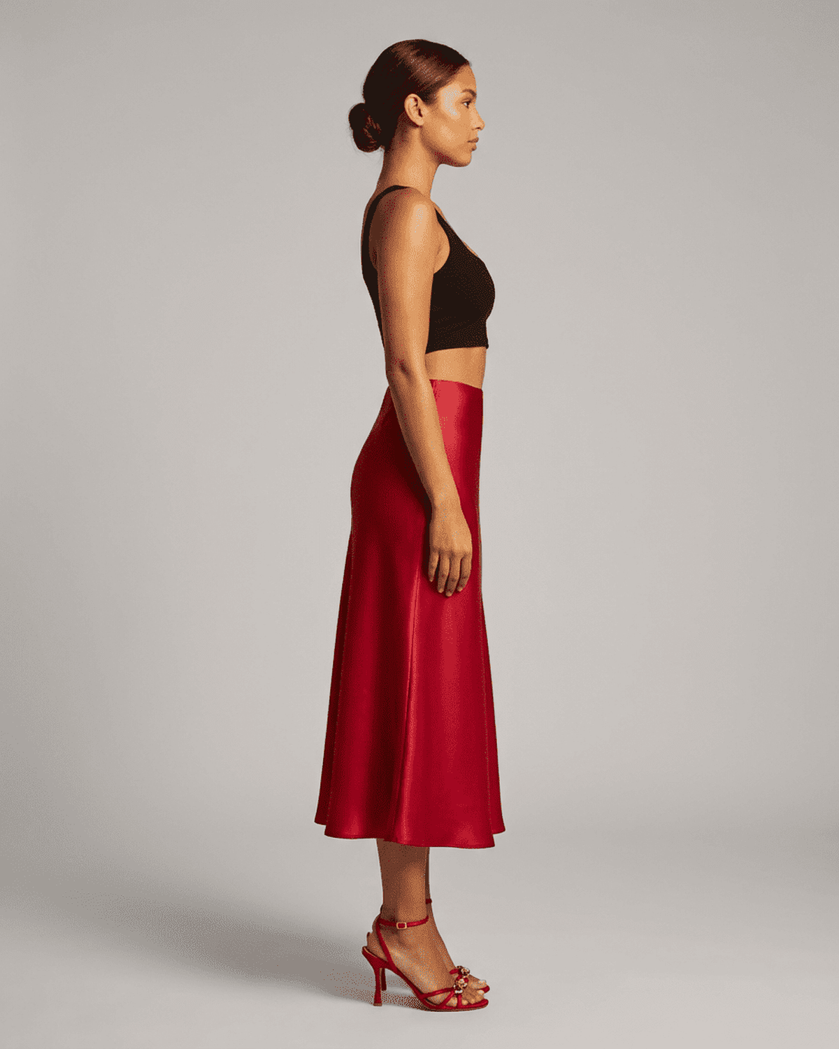 Model in profile wearing the Rosalia Midi Skirt by SLIMONA, showcasing its elegant satin mermaid design.