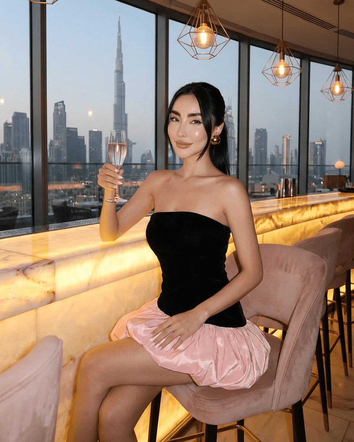 Model in Selina Mini Dress by SLIMONA, showcasing velvet and pink puff skirt in a stylish bar setting.