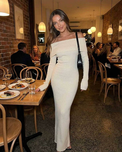 Sienna Maxi Dress by Lauven worn by a model in a restaurant, featuring an ivory off shoulder design and ribbed knit fabric.