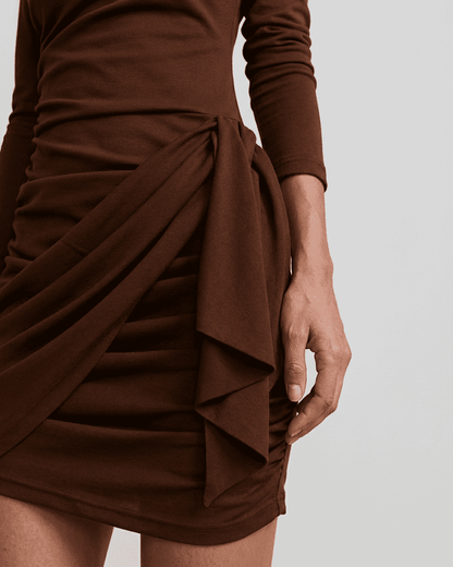 Sienna Mini Dress by SLIMONA features stylish side draping and ruched detailing for a chic look.