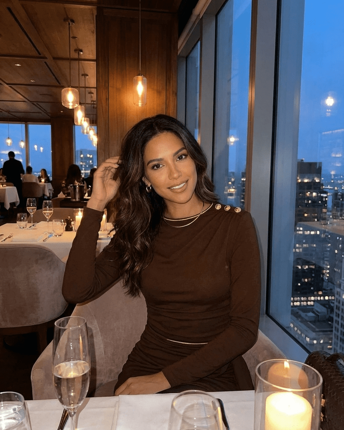 Sienna Mini Dress by SLIMONA worn in a chic restaurant setting, featuring a ruched fitted silhouette and elegant round neckline.