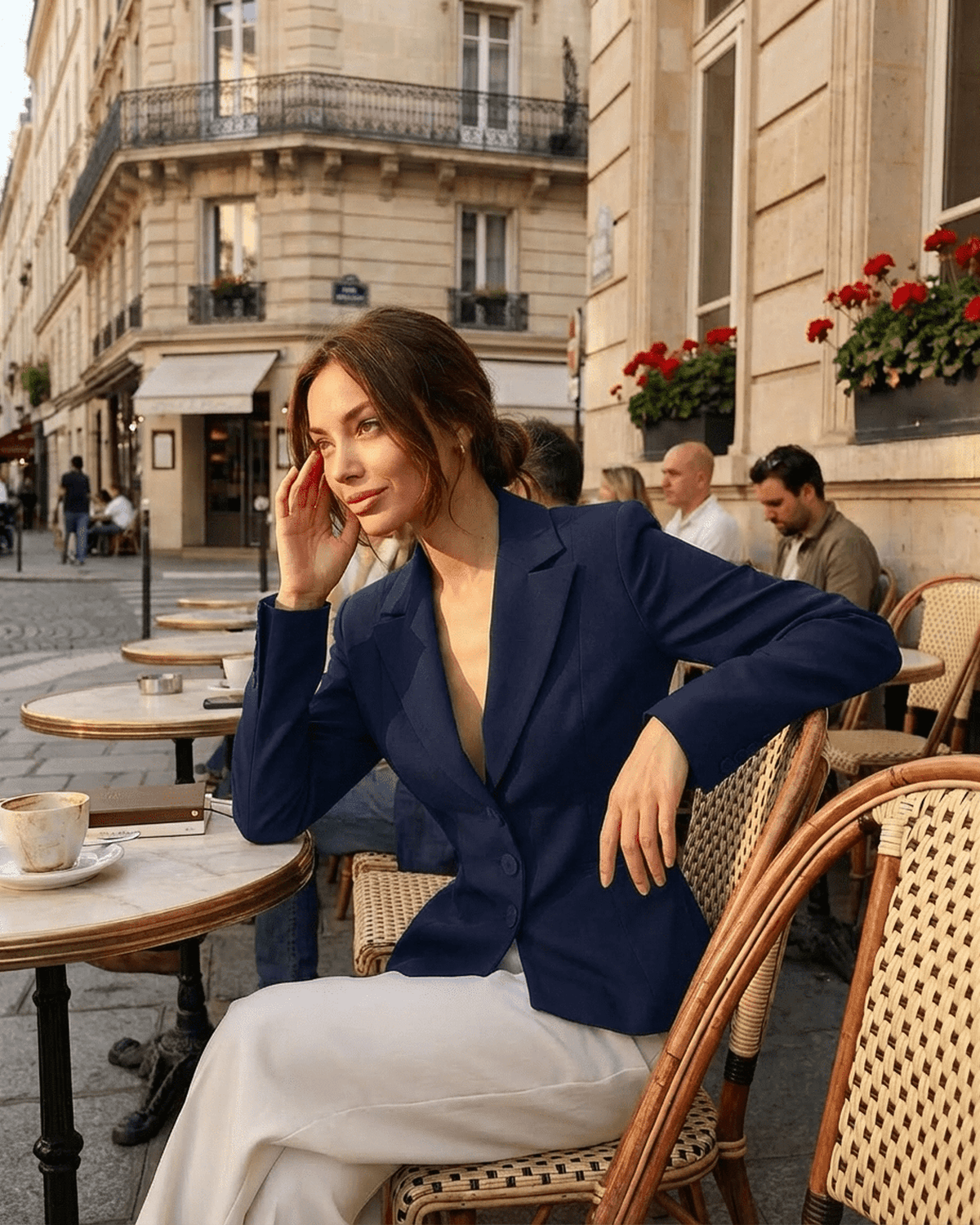Woman wearing SLIMONA Aurora Blazer, fitted navy V-neck tailored jacket at a chic Parisian café.