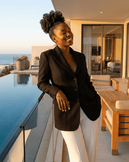 Woman wearing Celeste Blazer by SLIMONA, showcasing its tailored V-neck design by a poolside.