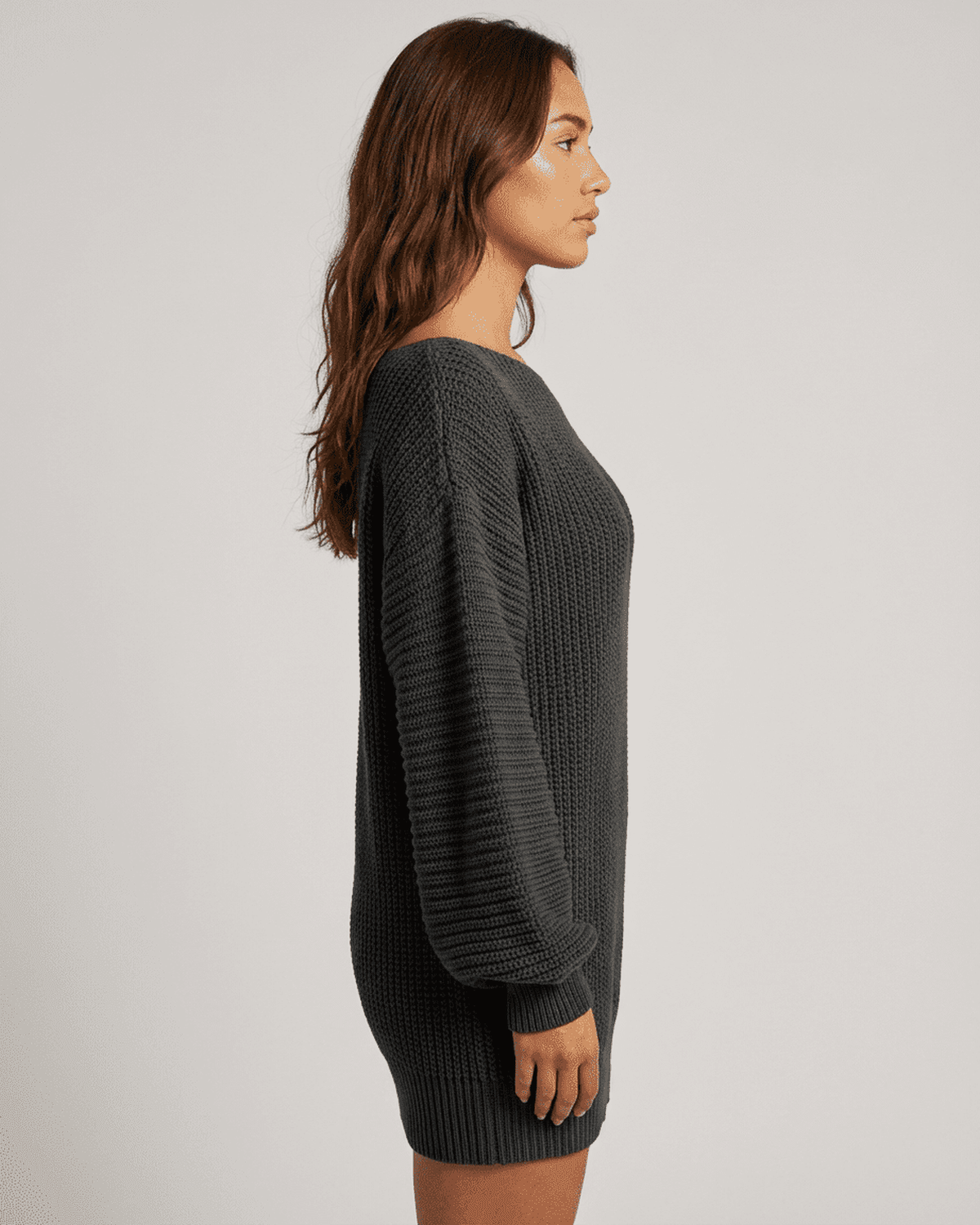 Side view of a model wearing the SLIMONA Ember Mini Dress in deep charcoal ribbed knit with lantern sleeves.