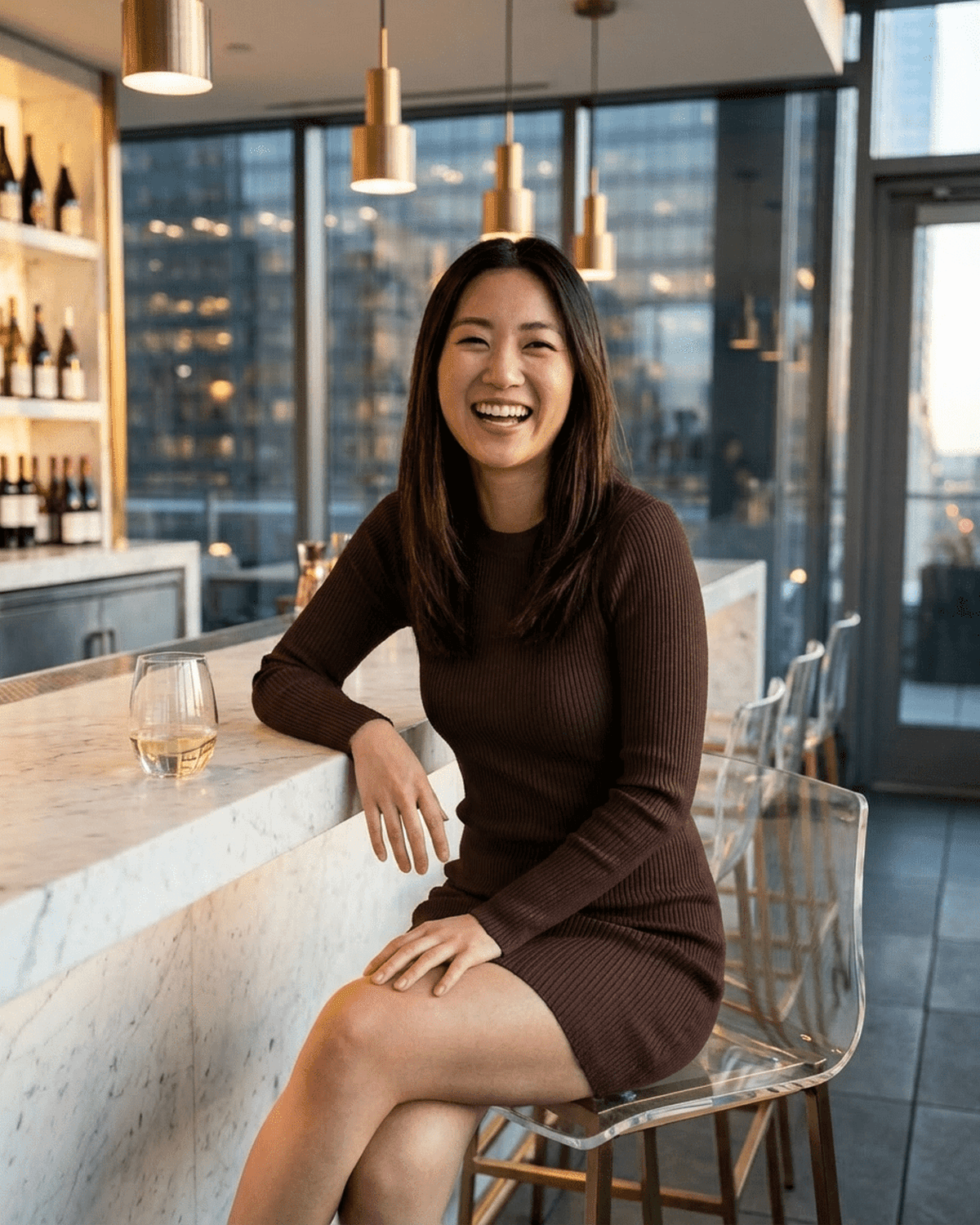 Woman in a ribbed knit Florence Mini Dress by SLIMONA, smiling at a bar with a drink.