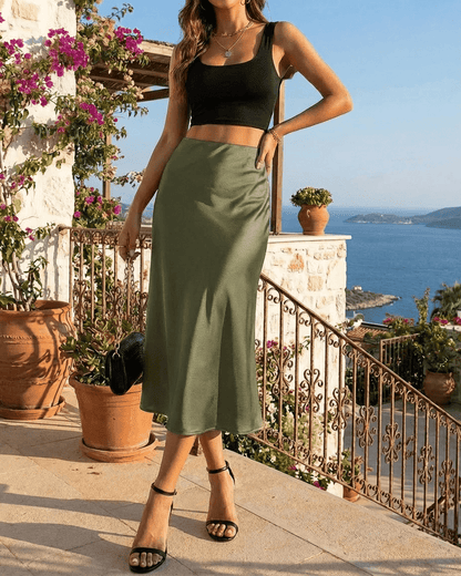 Olivia Midi Skirt by SLIMONA, elegantly styled in olive green satin by the sea.
