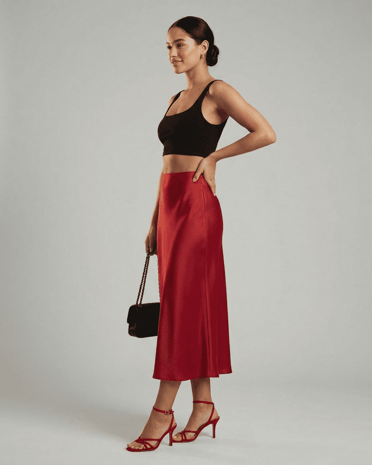 Stylish model showcases the Rosalia Midi Skirt by SLIMONA, featuring a rich red satin mermaid design.