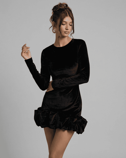 Model wearing Velora Mini dress black by SLIMONA, showcasing luxe velvet and pleated hem in a fitted bodycon silhouette.