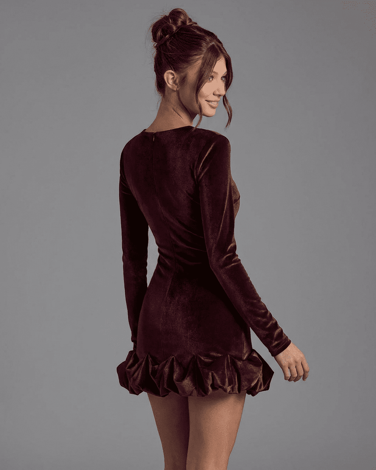 Woman wearing Velora Mini Dress by SLIMONA, showcasing the back view with pleated hem in deep burgundy.