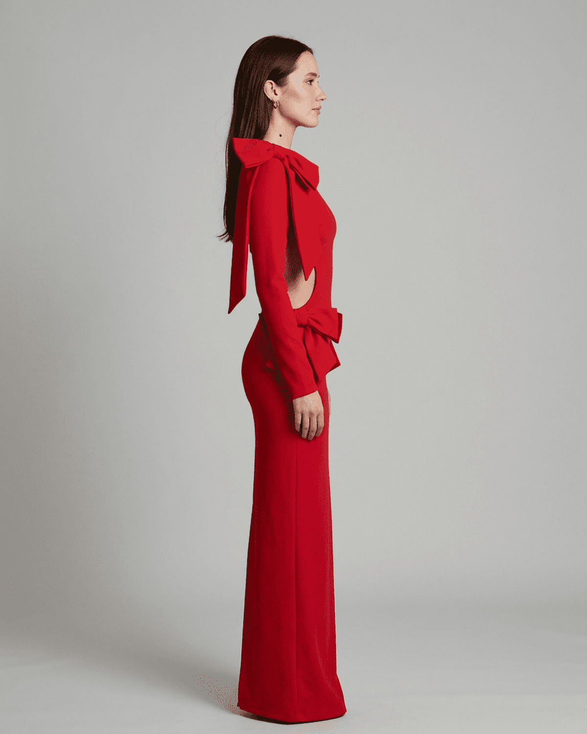 Side view of a model wearing the Valencia Maxi Dress by SLIMONA, showcasing its cut-out waist and sculptural bows.