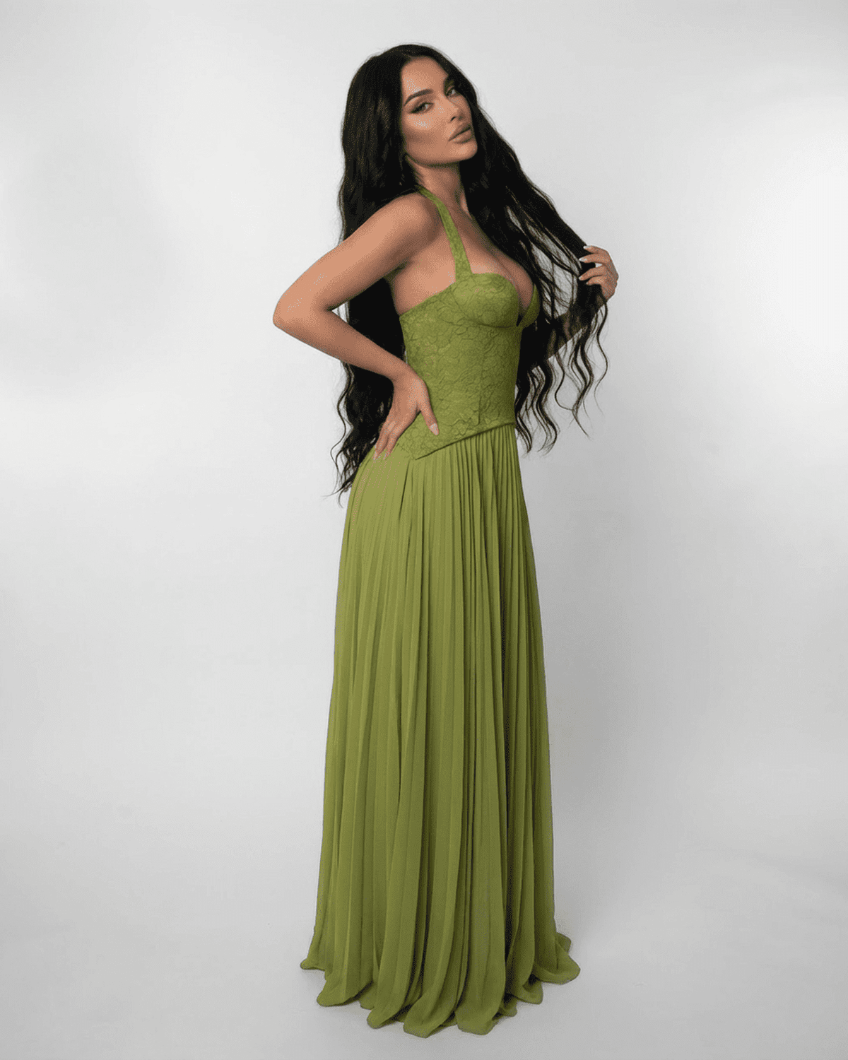 Model showcasing the SLIMONA Verdant Maxi Dress with a lace bodice and pleated skirt in olive green.