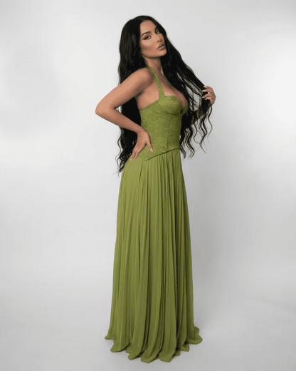 Model showcasing the SLIMONA Verdant Maxi Dress with a lace bodice and pleated skirt in olive green.