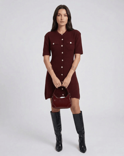 Model wearing Viera Mini Dress by Lauven in burgundy with button closure and stylish bag.